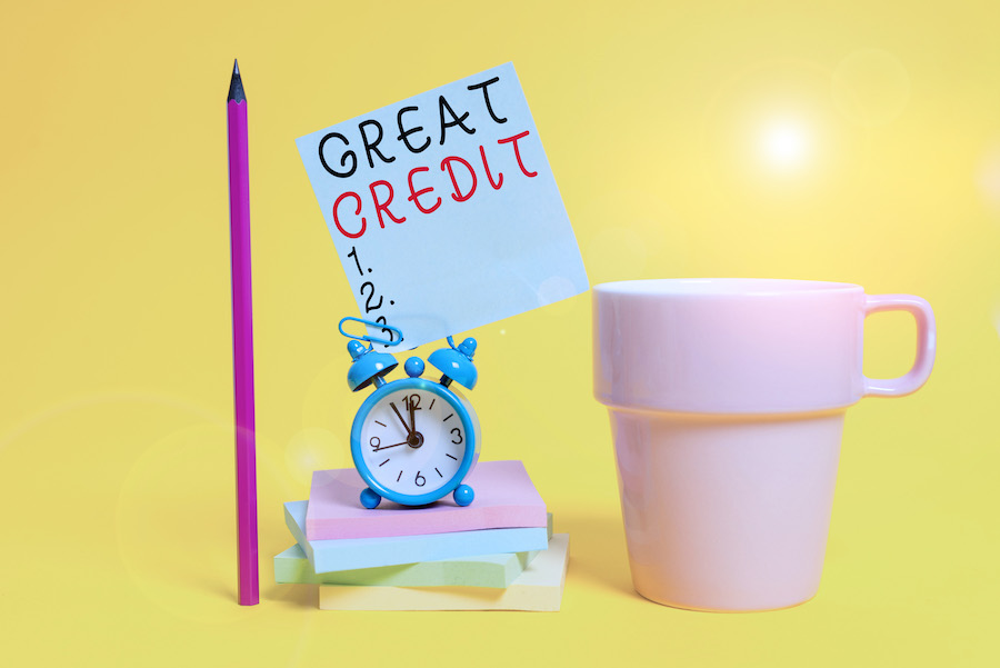 A photo of an alarm clock, book, and mug showcasing how to improve credit score fast