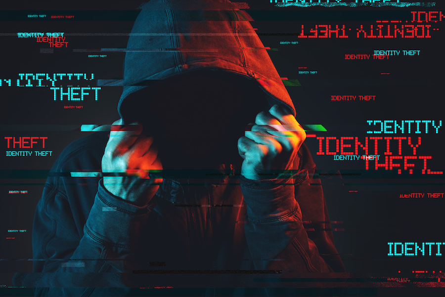 Online identity theft concept with faceless hooded male person, low key red and blue lit image and digital glitch effect