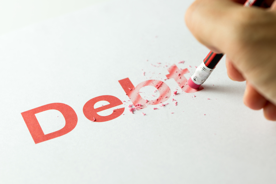 Close up of red pencil erasing the word debt on paper signifying removing accounts as credit score hacks