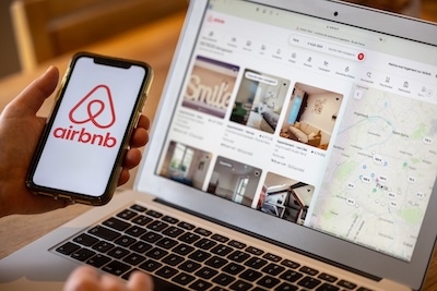 An image of person. holding a phone with Airbnb app open